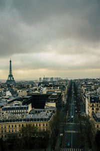 Distant view of eiffel tower in cityscape against cloudy sky