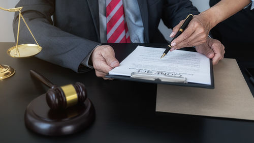 Midsection of man reading book on table