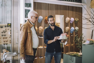 Salesman showing cap to senior male customer at clothing store