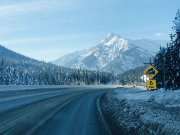 Road by snowcapped mountains against sky