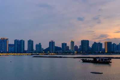 River by buildings against sky during sunset