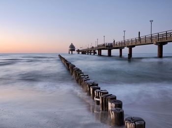 Pier over sea against sky during sunset