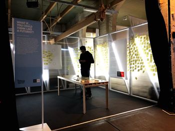 Rear view of man standing in illuminated room