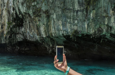 Close-up of person using mobile phone in sea