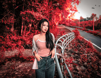 Full length of young woman standing against red wall