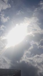 Low angle view of sunlight streaming through clouds