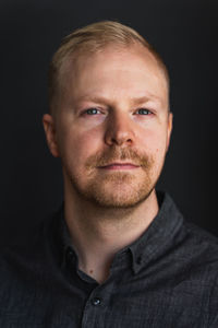 Close-up portrait of young man against black background