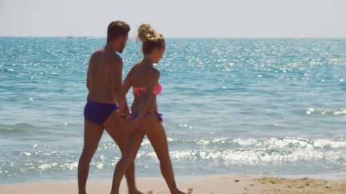 Side view of friends standing on beach