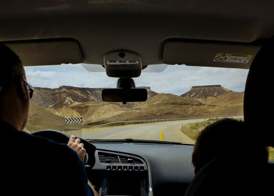 Boy sitting by father driving car on highway