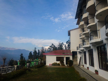 Houses by buildings in city against sky