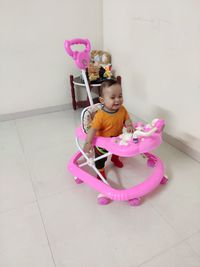 Cute girl looking at camera while sitting on tiled floor