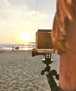 Close-up of woman photographing sea at sunset