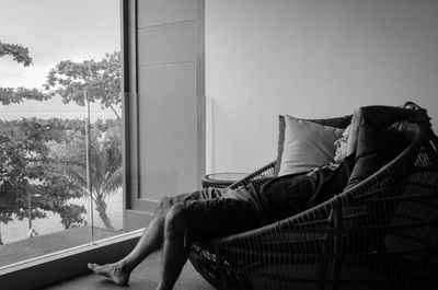 Side view of man relaxing on seat at home