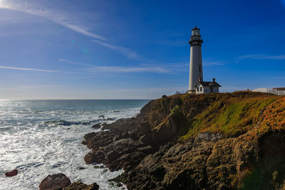 Lighthouse by sea against sky