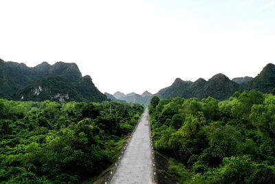 Road amidst green mountains against clear sky