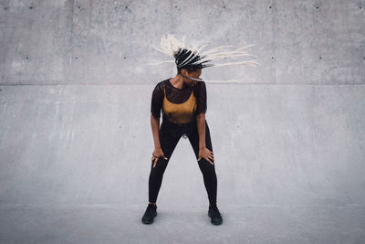 Full length of teenage girl with tousled hair dancing at skateboard park