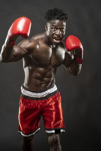 Shirtless boxer standing against black background