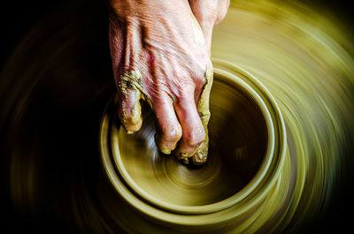 Cropped hand of potter making earthenware at pottery workshop