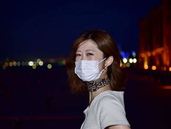 Portrait of young woman in illuminated city at night