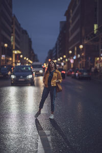 Portrait of young woman standing on road in city at night
