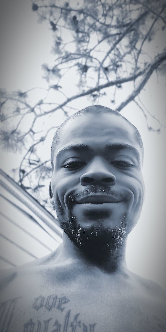 portrait, tree, headshot, low angle view, close-up, nature, human representation, people, front view, representation, human body part, looking at camera, plant, day, outdoors, sky, beard, lifestyles, human face