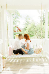 Couple sitting on swing in terrace