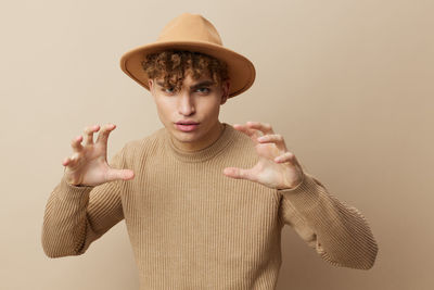 Portrait of man wearing hat against beige background