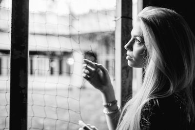 Side view of thoughtful young woman standing by window