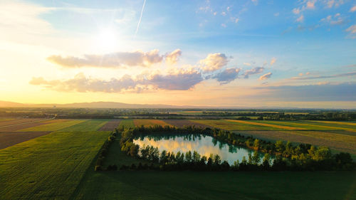 Scenic view of agricultural field against sky during sunset