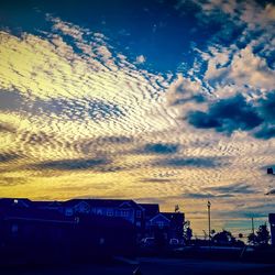 Illuminated buildings against cloudy sky