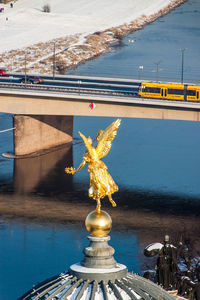 Gold angel statue on academy of fine arts dresden dome against river