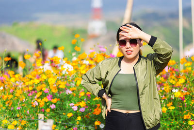 Young woman shielding eyes while standing against plants