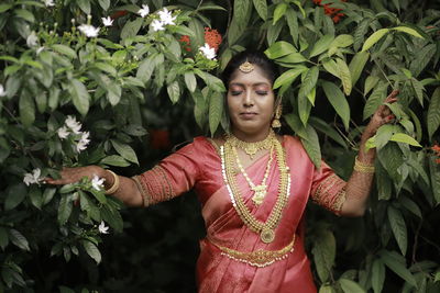 Portrait of young woman standing against plants