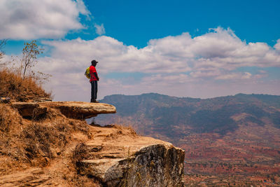 A hiker standing on a rock at a scenic lookout against valley and mountains in makueni county, kenya