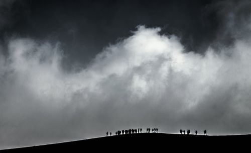 Low angle view of silhouette trees against cloudy sky