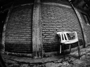 Abandoned chair against brick wall