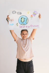 Smiling girl holding poster of earth planet at home