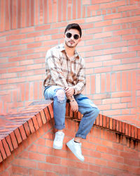 Portrait of young man sitting against wall