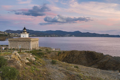 Scenic view of building by mountains against sky during sunset