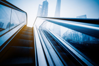 Escalator in modern building against sky