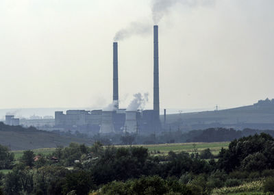 Smoke emitting from factory against sky