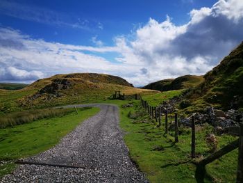 Road leading towards mountains against sky