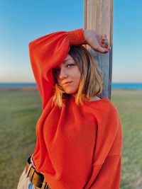 Portrait of beautiful young woman standing against sky