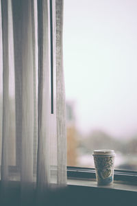 Close-up of coffee cup against window