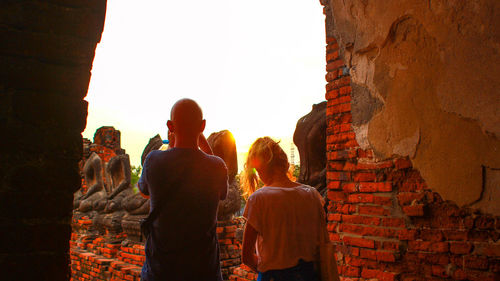 Rear view of people standing against wall