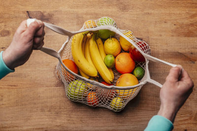 High angle view of hand holding fruits on table