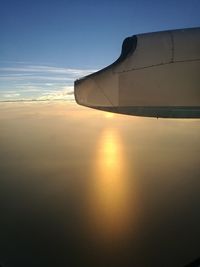 Close-up of airplane wing against sky during sunset
