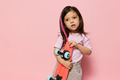 Portrait of smiling young woman standing against pink background