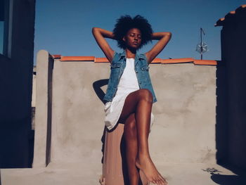 Portrait of beautiful young woman standing against sky