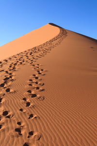 Sand dunes in desert against clear blue sky